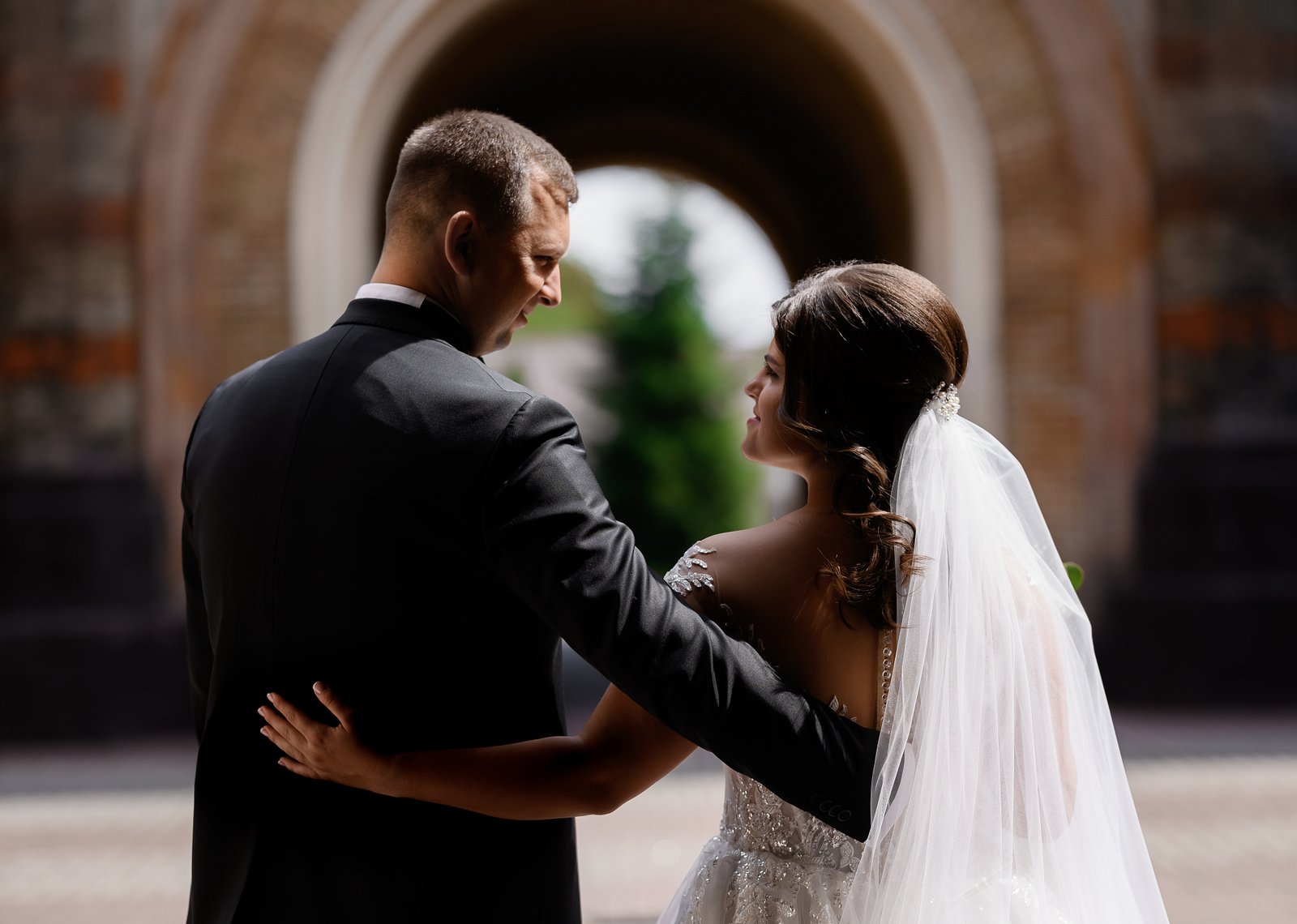 Back View Romantic Bride Groom Wearing Trendy Wedding Clothes Hugging Looking Each Other While Walking Through Ancient Arch Building Wedding Day